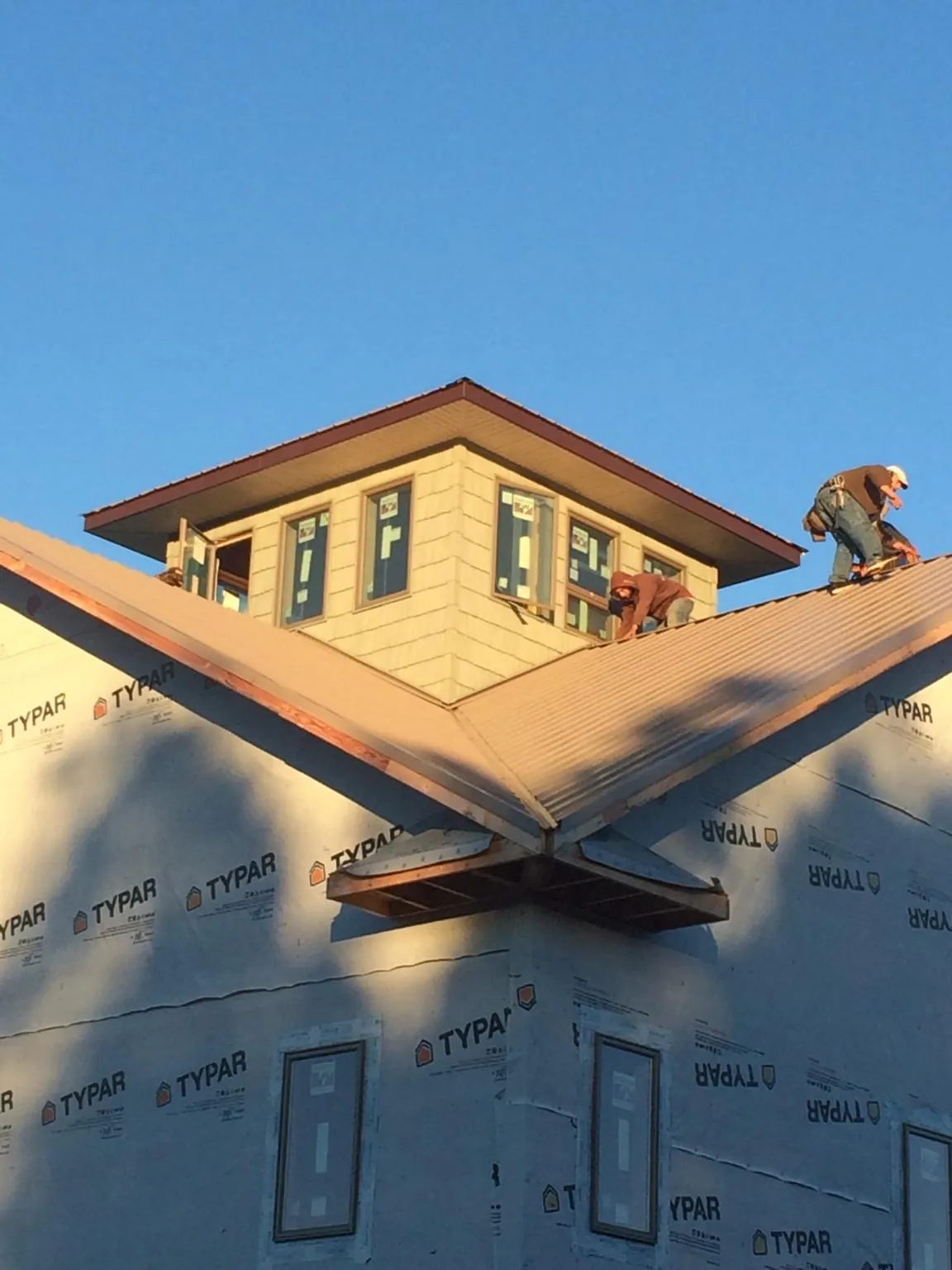 Roofers working around a rooftop cupola on a new metal roof at sunset — Roof Waterproofing in Vinton by Roofing Brothers
